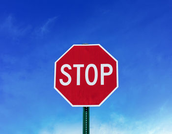 Low angle view of road sign against blue sky