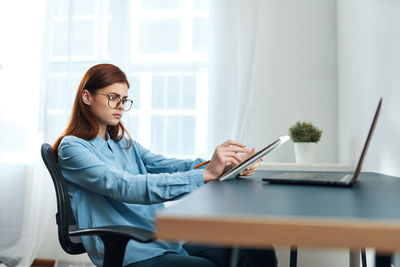 Young woman using mobile phone while sitting at home