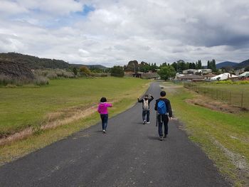 Rear view of people walking on road against sky