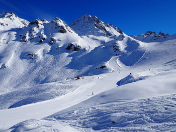 Scenic view of snowcapped mountains against blue sky on sunny day