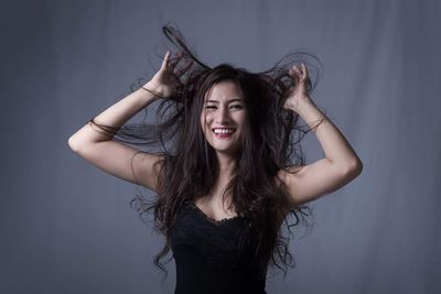 Portrait of smiling young woman against gray background