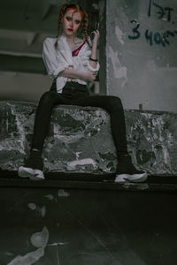 Full length of angry woman sitting on retaining wall