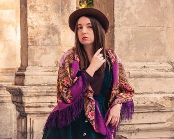 Portrait of beautiful young woman standing against wall