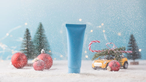 Mockup of a blue tube with a cosmetic product on a christmas background with falling snow. 