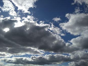 Low angle view of sunlight streaming through clouds