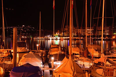 Rear view of illuminated boats moored in harbor at night