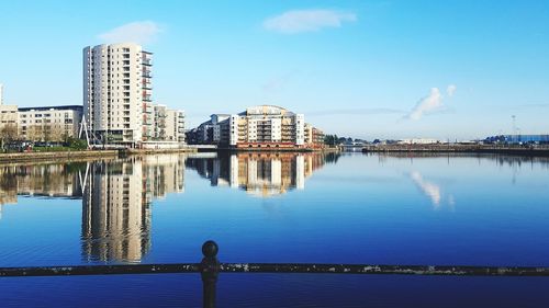 Reflection of buildings in calm water against sky