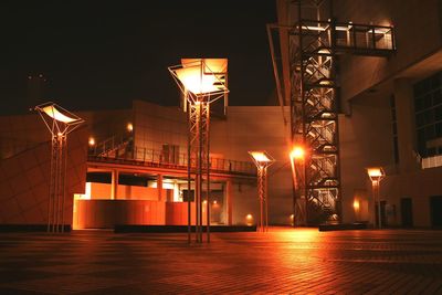 Low angle view of illuminated street lights by buildings at night