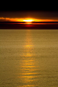 Scenic view of sea against dramatic sky during sunset