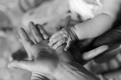 Cropped hands of mother and baby at home