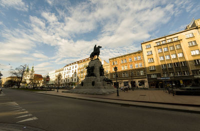 Statue on road by buildings against sky