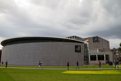 People in lawn against cloudy sky