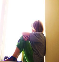 Rear view of young woman looking through window