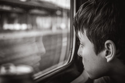 Close-up of boy looking through window while sitting in car