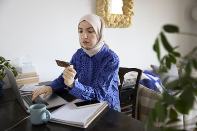 Woman in headscarf paying bills online at home