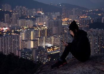 Woman standing on illuminated city street at night