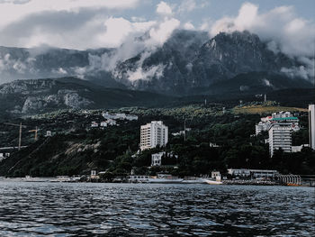 Scenic view of buildings by sea against sky