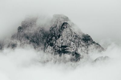 Scenic view of rocky mountains covered with clouds