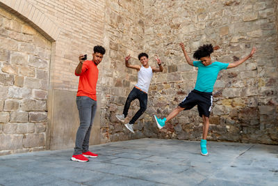 Full length of young man jumping against wall