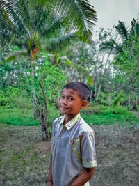 Portrait of young man standing against trees