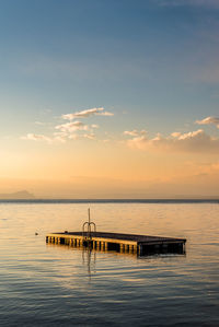 Floating platform on sea against sky during sunset