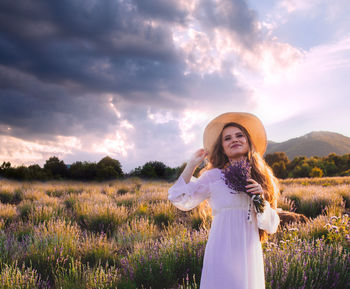 Woman standing on field against sky during sunset