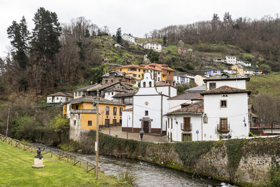 Houses by river and buildings against sky