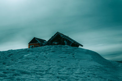 Building on snow covered landscape against sky