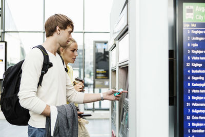 Friends standing by atm at railroad station