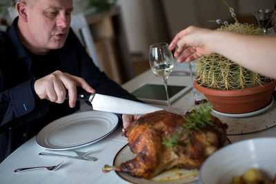 High angle view of family eating meat on dining table at home