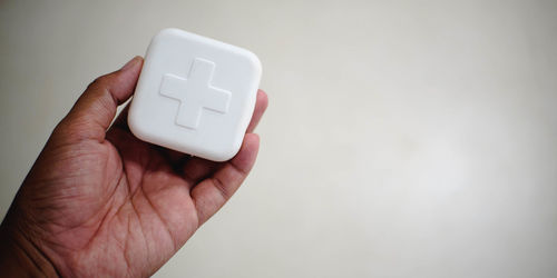 Close-up of hand holding medicine box against white background