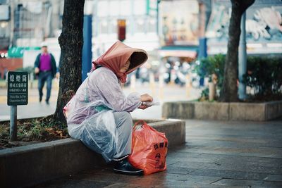 Side view of boy sitting on footpath