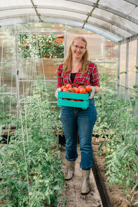 Full length of young woman standing in greenhouse