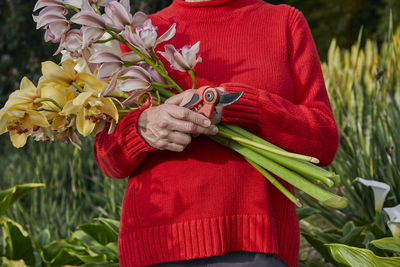 Older woman holding fresh cut bouquet of flowers in her garden