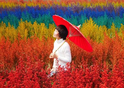 Woman with umbrella standing amidst multi colored plants