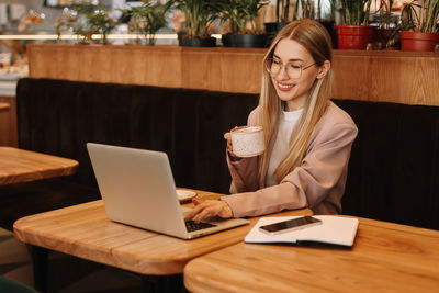 A business woman with glasses works online using a laptop. a student studies online sitting in cafe