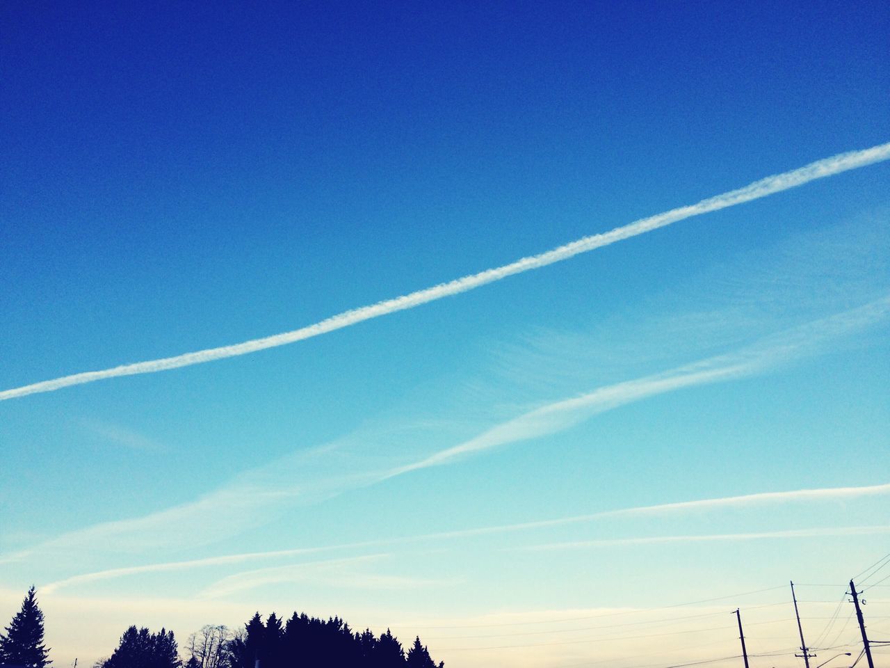 blue, low angle view, beauty in nature, tranquility, scenics, sky, vapor trail, tranquil scene, nature, tree, silhouette, copy space, clear sky, idyllic, outdoors, cloud - sky, no people, day, cloud, majestic