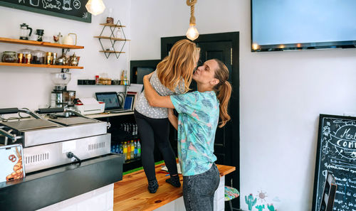 Mother kissing daughter standing on table