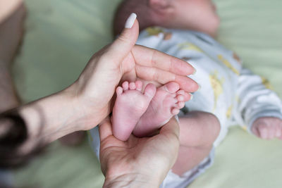 Midsection of mother holding baby hands