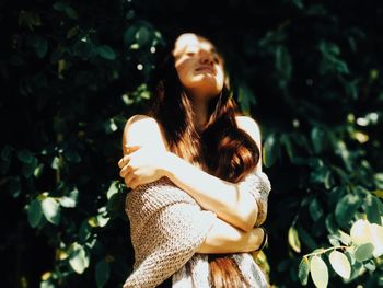 Young woman looking away while standing on tree