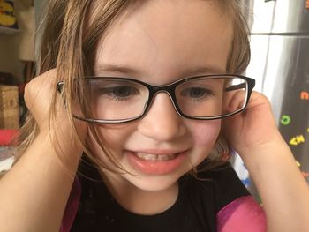 Close-up of smiling girl wearing eyeglasses looking away at home