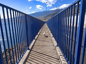 View of footbridge against blue sky