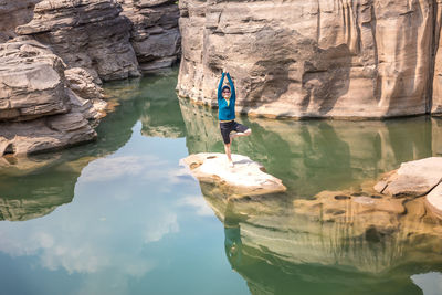 Reflection of woman on rock by lake