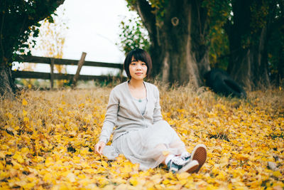 Young woman sitting on field during autumn