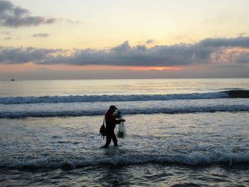 Woman on beach against sky during sunset