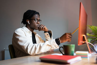 Serious focused african american man student looking attentively at monitor sits at office desk