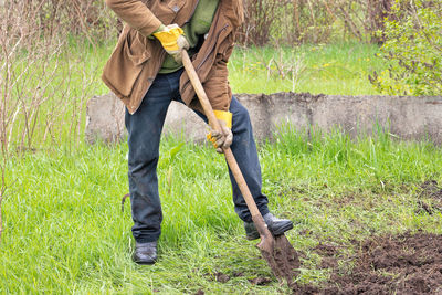 A farmer digs up a bed with a shovel in early spring