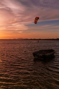 Scenic view of sea against sky during sunset, with a kite surf in the background