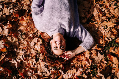 Directly above shot of woman lying down on leaves at park