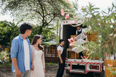 Side view of couple standing against trees